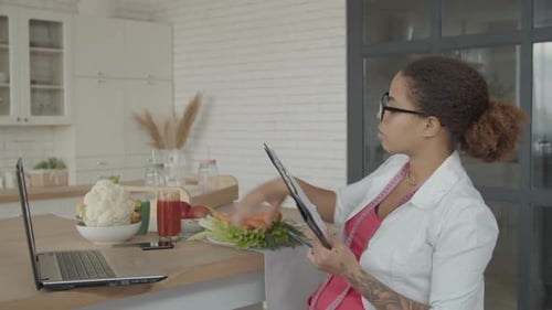 Woman Taking Notes With Healthy Food on Counter