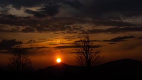 Sunset Behind Silhouetted Mountains and Bare Trees