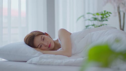 Smiling Young Woman Waking Up in Bed