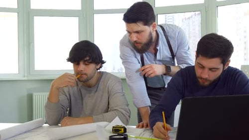 Team Collaborating on Blueprints in Modern Workplace