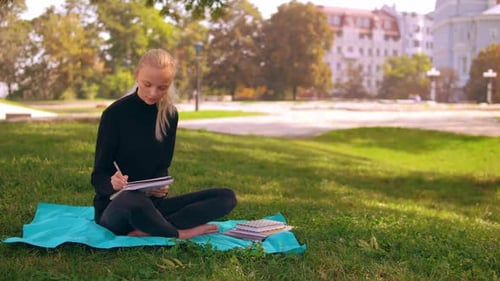 Young Woman Writing in Notebook in City Park
