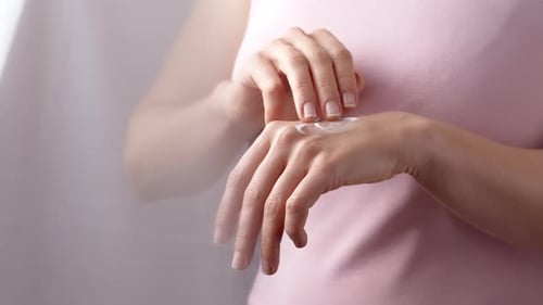 Woman Applying Moisturizer to Her Hand
