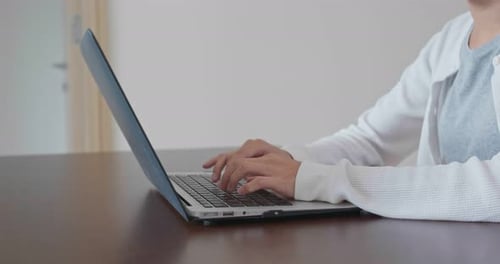 Woman using laptop at a wooden table