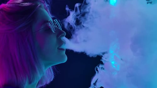 Young Woman Vaping in Neon Futuristic Setting Young Woman Vaping in Neon Futuristic Setting