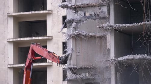 Mechanical Arm Demolishing Concrete Building in City