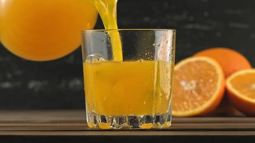 Orange Juice Being Poured Into Glass with Ice