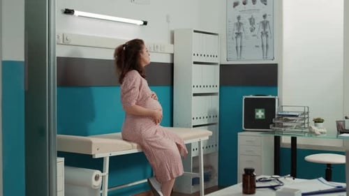 Portrait of Young Woman with Pregnancy Belly Sitting in Medical Office