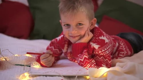 Boy in Christmas Sweater Drawing on Bed
