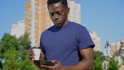 Young Adult Using Phone with Coffee in City