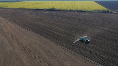 Vista aérea de un tractor que irriga un campo agrícola