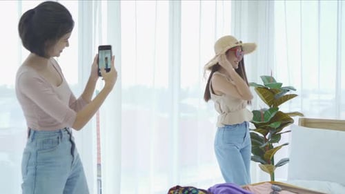 Young Women Taking Photos in Bedroom with Smartphone