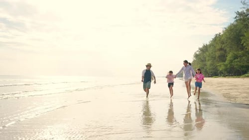 4K Asian family parents with two little daughter playing on the beach together at summer sunset.