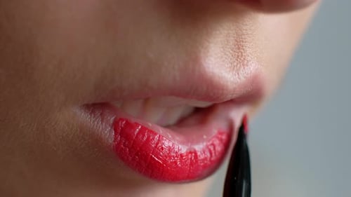La chica se maquilla los labios. Aplicando lápiz labial rojo en los labios. Primer plano.