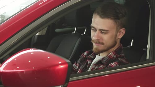 Young Man Smiling in a Red Car
