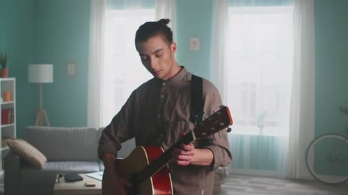 Young Man Plays Guitar in Living Room