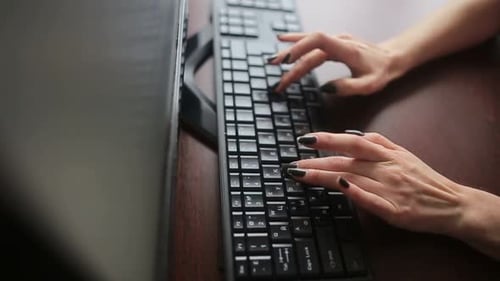 Seitenansicht einer afrikanischen Geschäftsfrau im Kleid, die auf einem Sessel neben dem Fenster sitzt und Laptop benutzt