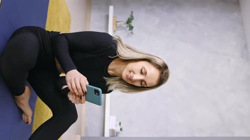 Smiling Woman Using Phone After Yoga at Home