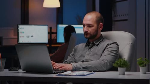 Man Working on Laptop at Night in Office