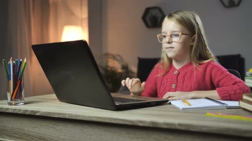 Fröhliches Kind macht Hausaufgaben online mit Laptop