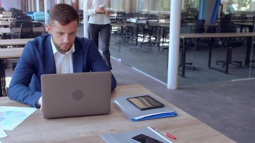 Young Adult Working On Laptop in Modern Office