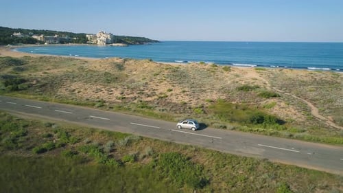 Aerial View of Car Driving on Coastal Road Next To Beautiful Wild Beach