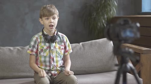 Portrait of child blogger talking on camera in a studio, he recording video blog