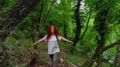 Woman Hiking Downhill on Lush Forest Trail