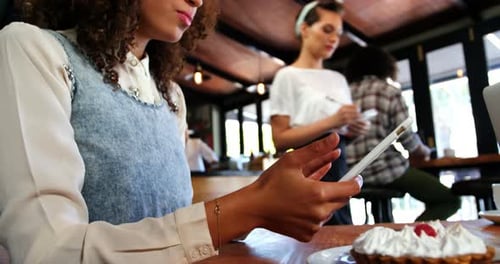 Young Woman Using Tablet in Busy Cafe