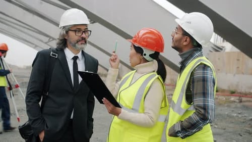 Construction Workers Discussing Project with Manager Standing in Building Area