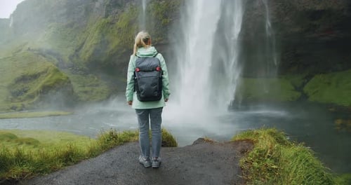 Blond Woman Stays in Front of Beautiful Seljalandsfoss Waterfall Iceland
