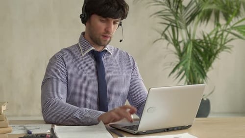 Professional Man Working on Laptop with Headset