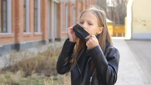 Girl Puts on Protective Face Mask Outside