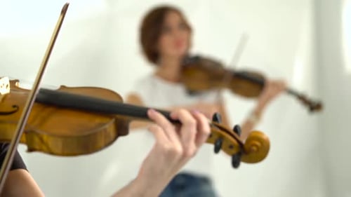 Two Women Performing with Violins Indoors