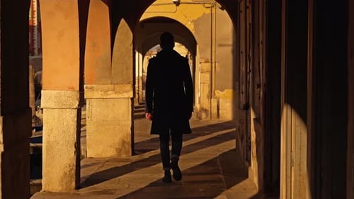 Guy in Dark Coat Walks Along Arch Passage on Embankment