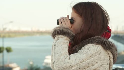 Girl Looks Through Binoculars Near Urban River