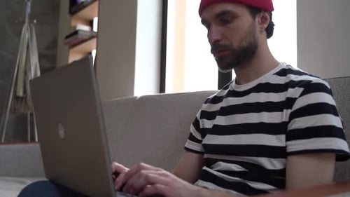 Man Typing on Laptop While Sitting on Couch