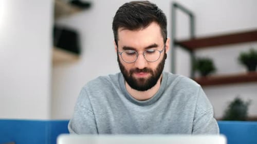 Man With Glasses Working on Laptop Indoors