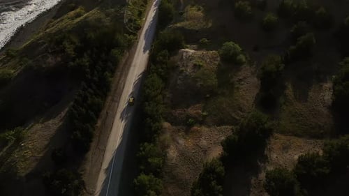 A Car Drives Along a Coastal Road Over a Picturesque Rocky Shore