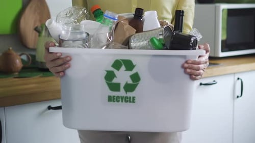 Person Carrying Recycle Bin in Home Kitchen