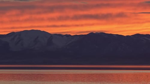 Feuriger Sonnenuntergang über Bergen, die sich im See spiegeln