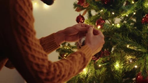 Man Decorating Christmas Tree with Ornaments at Home