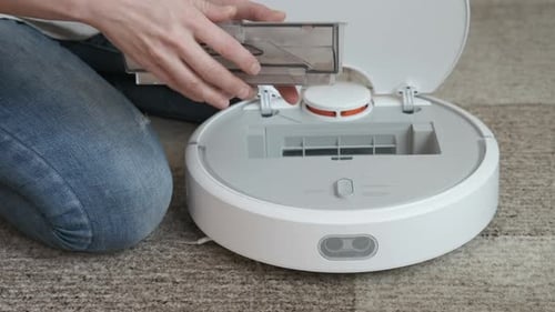Woman empties robotic vacuum cleaner dust container