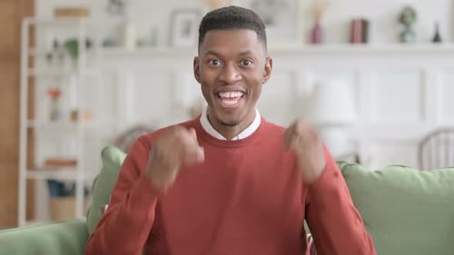 Excited Man Celebrates Success on Couch Indoors