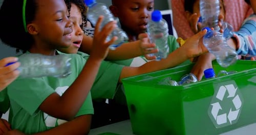 Children Recycling Plastic Bottles in Green Bin