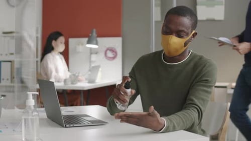 Person Using Hand Sanitizer at Office Desk