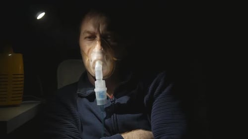 un homme prend des inhalations à l'aide d'un nébuliseur