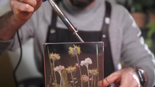 Adult Craftsperson Soldering Glass Art Piece