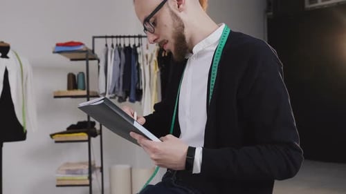 Designer Sits on the Table and Draw Sketches in the Studio