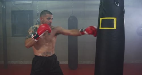 Male Boxer Punching Boxing Bag in Gym