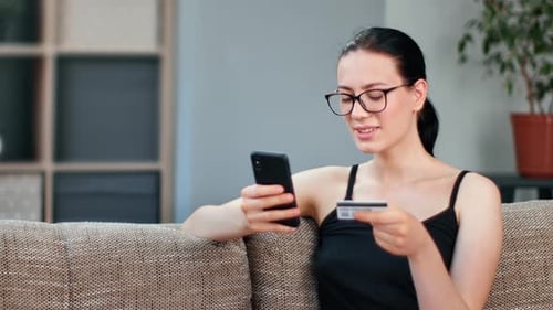 Cheerful Young Modern Mixed Race Female Paying Order Goods Online Use Smartphone and Credit Card